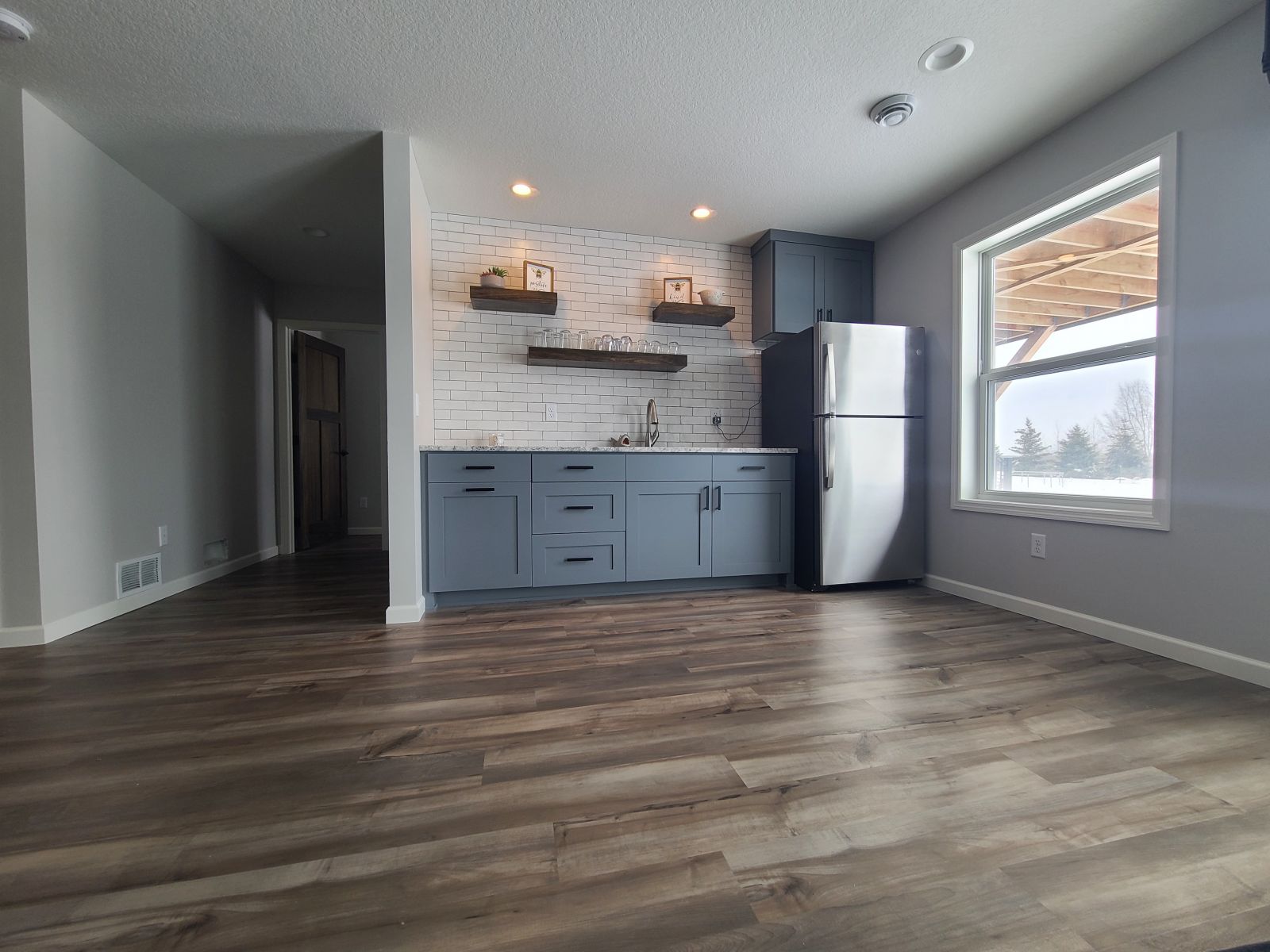 Finished basement living space with kitchenette, durable flooring and natural light
