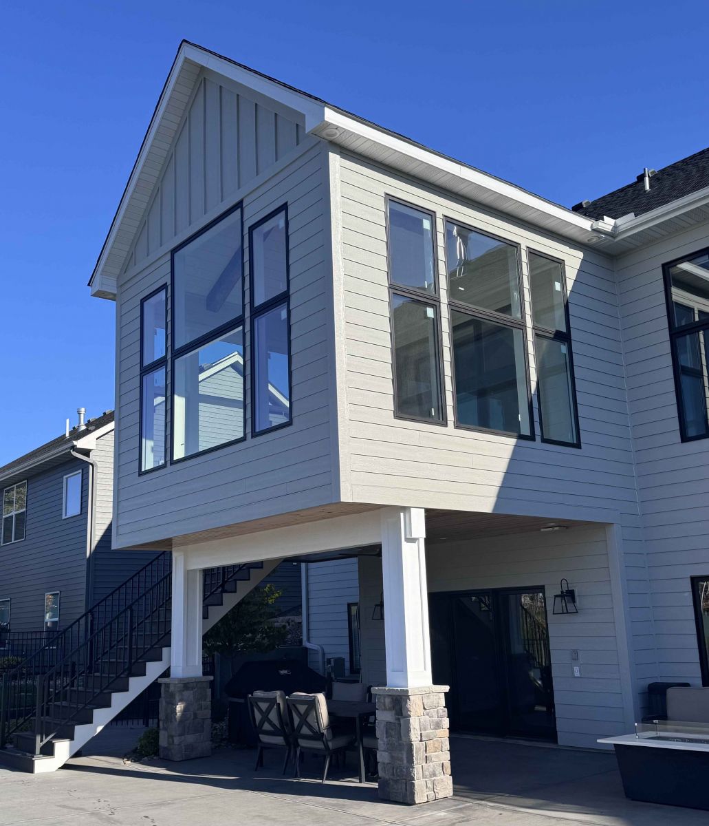 Close view of a porch addition with tall black-framed windows and coordinated gray siding