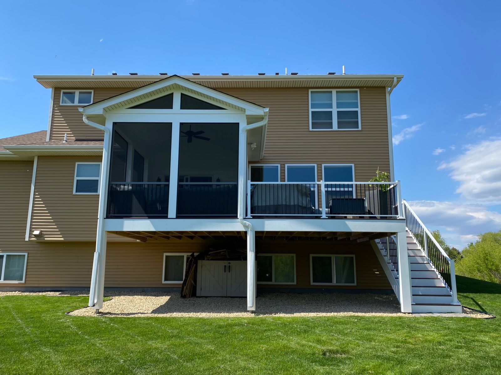 Elevated screened porch with white trim attached to a tan Minnesota home